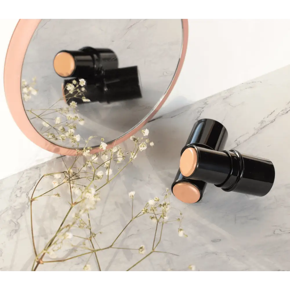 MIANIMED Premium skincare products reflected in a round mirror on a marble surface with flowers nearby.