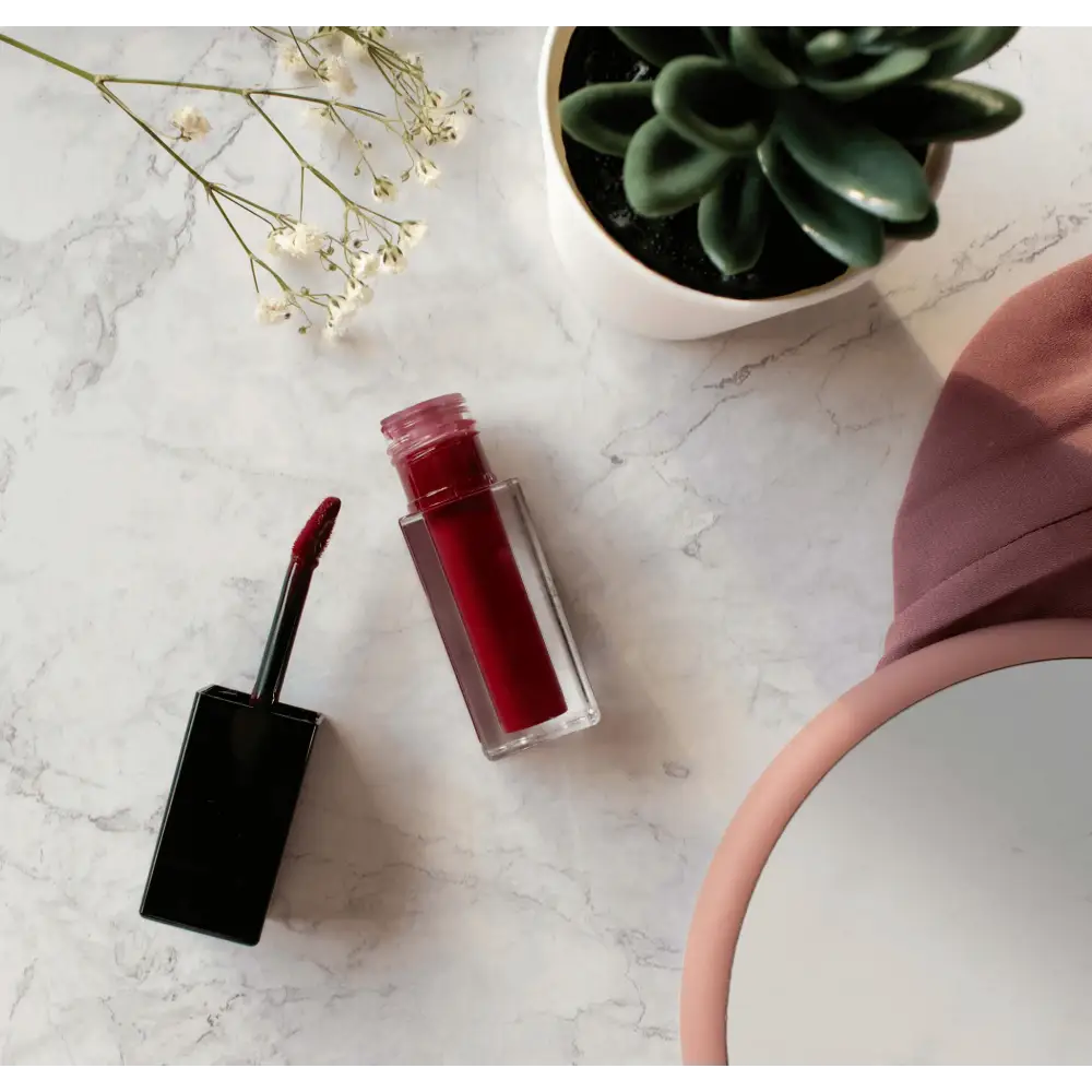 MIANIMED premium skincare red lipstick on marble surface with flowers and green succulent plant