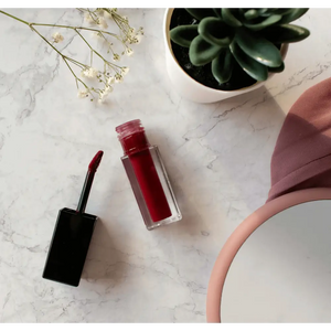 MIANIMED premium skincare red lipstick on marble surface with flowers and green succulent plant